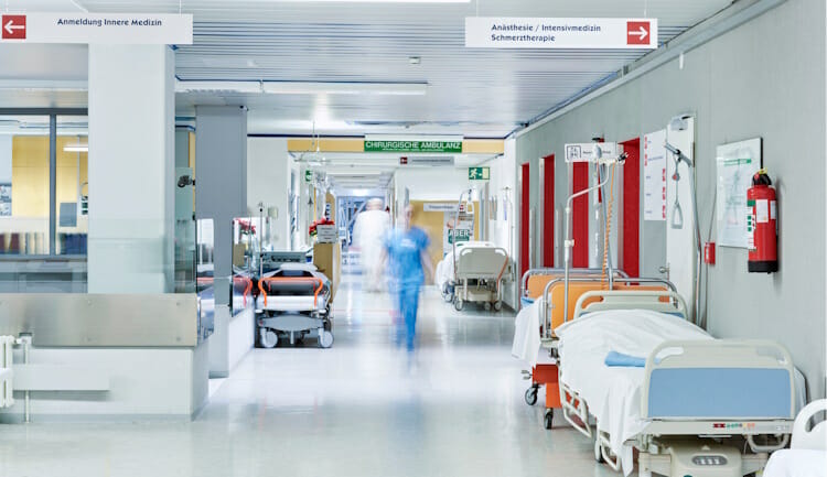 hospital hallway with beds and a nurse